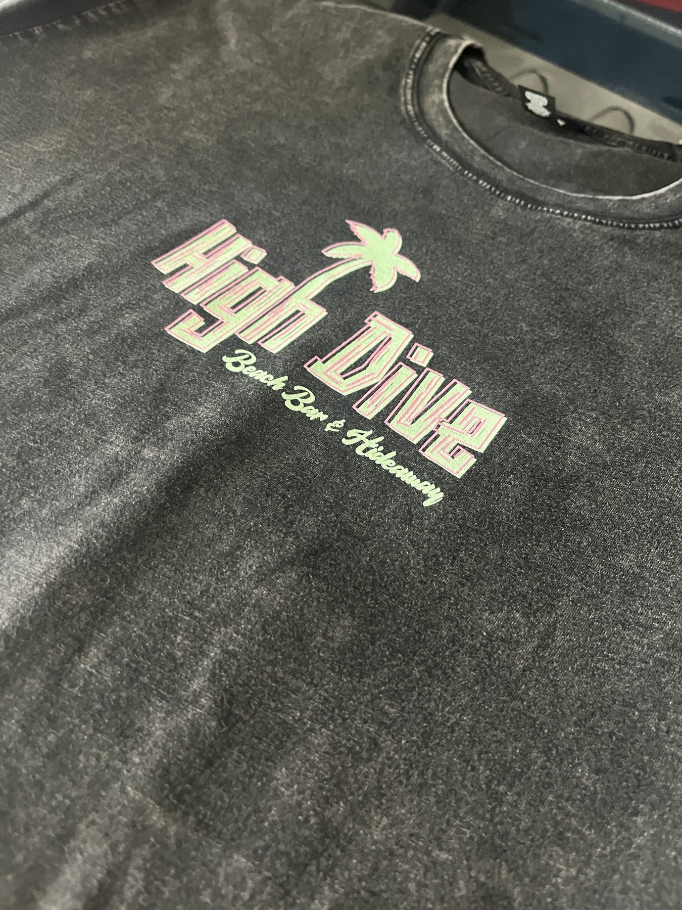 Pink and green High Dive screen print on a dark shirt