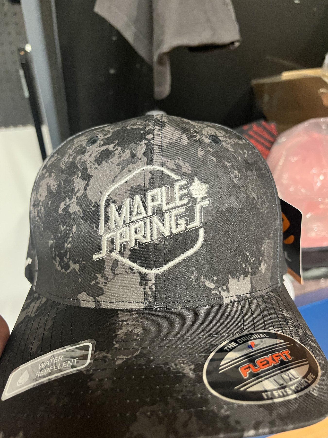 Camo Flexfit cap embroidered with the Maple Springs logo