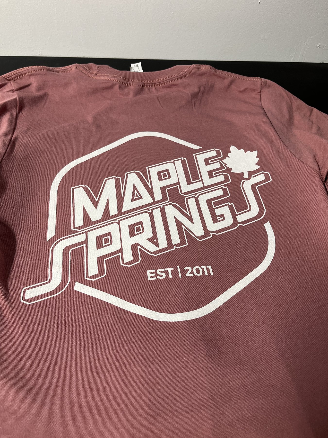 Cream Maple Springs graphic printed on a red shirt