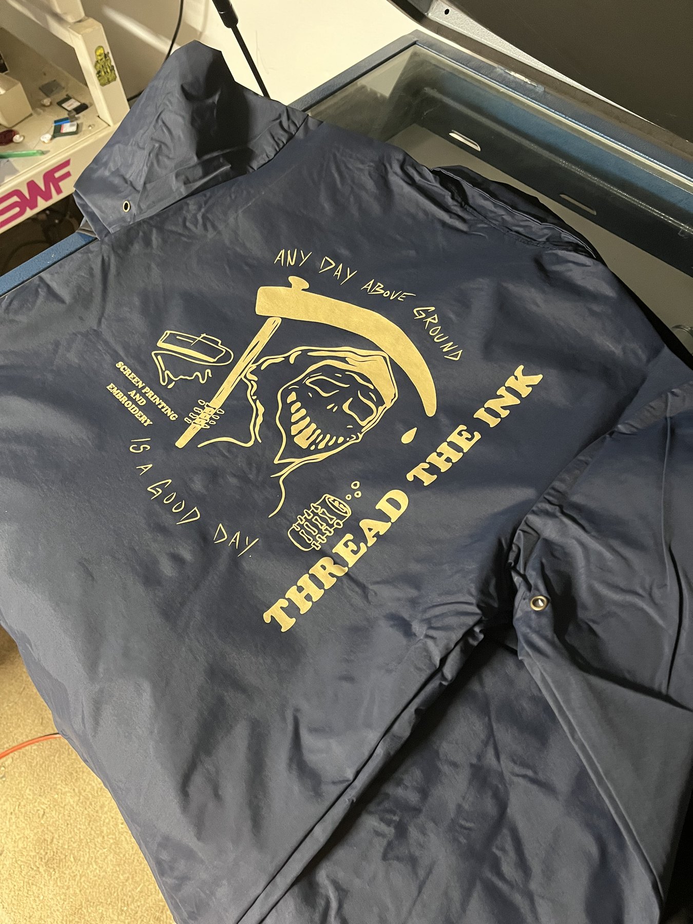 Gold Thread the Ink graphic printed on a navy jacket